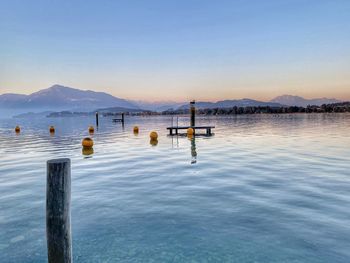 Wooden posts in lake against sky