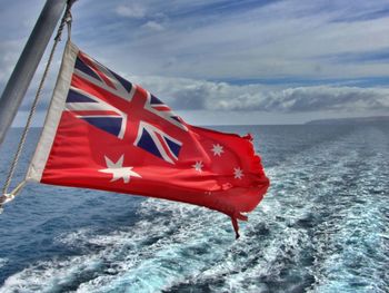 Red flag on sea against sky