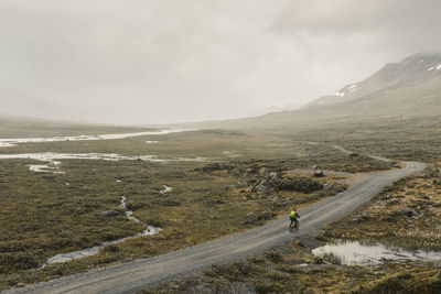 Person cycling through foggy mountain landscape