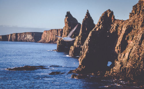 Scenic view of sea by mountain against sky