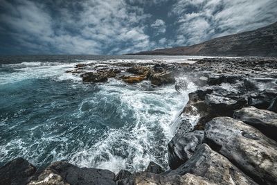 Scenic view of rocks on sea against sky