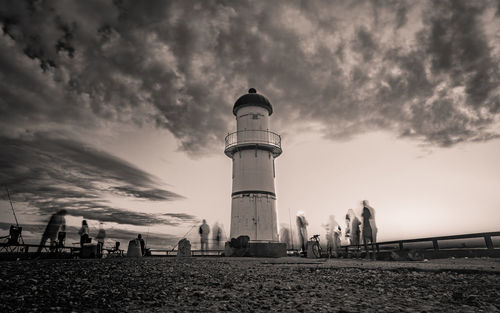 Lighthouse amidst buildings against sky during sunset