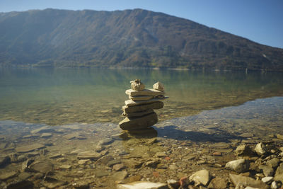 Stack of rocks at lakeshore against mountain