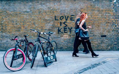 Full length of woman with bicycle standing against brick wall