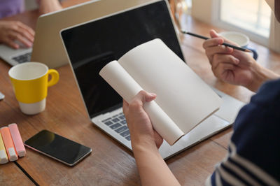Midsection of woman using laptop on table