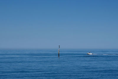 Sailboat in sea against clear blue sky