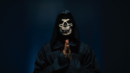 Young woman wearing mask against black background