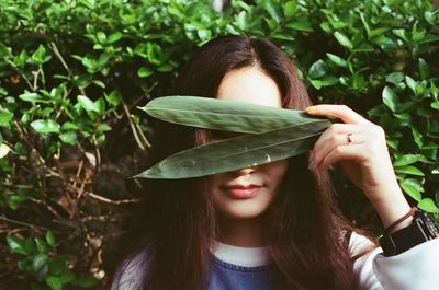 Portrait of young woman looking through leaves