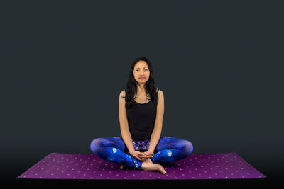 Portrait of woman sitting against black background