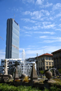 Fountain in city against sky