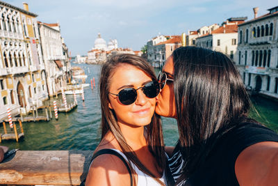 Woman kissing friend against canal in city