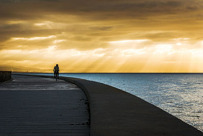 Man on sea against sky during sunset