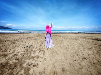 Rear view of woman on beach against sky