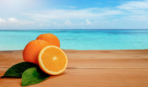 Orange fruit on table against sea