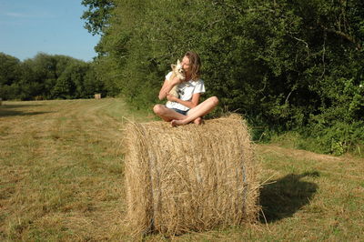 Side view of woman sitting on grassy field