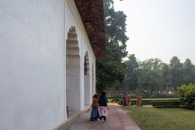 Rear view of women walking on building amidst trees