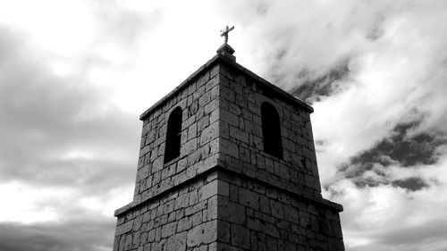 Low angle view of cross on building against sky