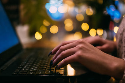 Midsection of woman using laptop at night