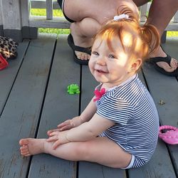 Cute girl sitting with low section of woman in background