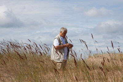 Mature man standing on field against sky