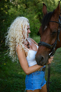 Beautiful woman with horse in summer park