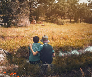 Rear view of friends sitting on field