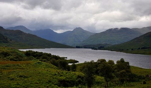 Scenic view of mountains and lake against cloudy sky