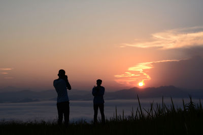 Silhouette friends standing against sky during sunset