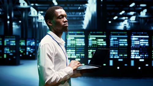 Young man using laptop while standing in office