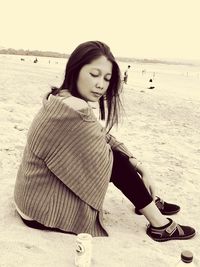 Beautiful young woman sitting on beach