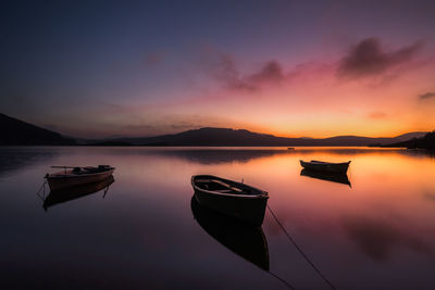 Boat moored in lake against sky during sunset