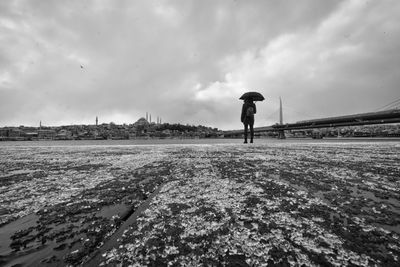 Man standing on shore against sky