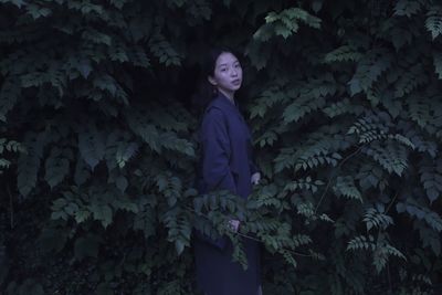 Portrait of woman standing against plants