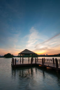 Pier in sea at sunset