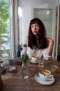 Portrait of young woman having coffee on table at cafe