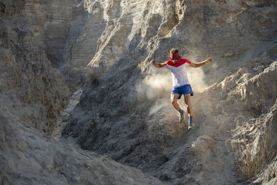 A man trail running down on technical terrain leaving dust on his way