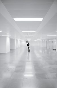 Rear view of woman standing in illuminated basement