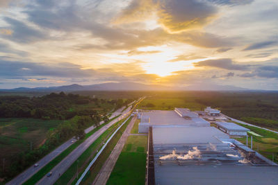 High angle view of road amidst field against sky during sunset