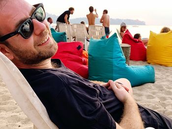 Smiling man wearing sunglasses while resting at beach