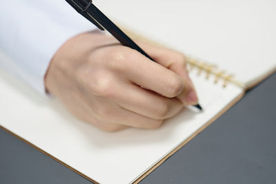 Cropped hand of woman writing in book