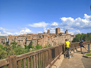 Rear view of people walking on bridge against sky