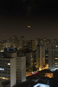 Illuminated buildings in city against sky at night