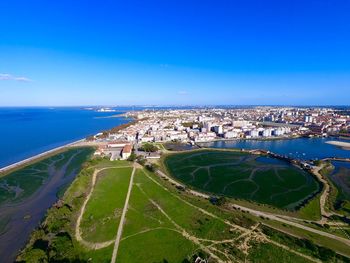 High angle view of sea and cityscape against blue sky