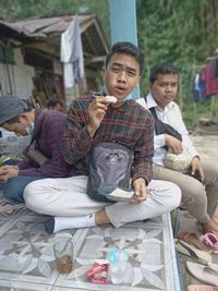 Full length of a boy drinking while sitting outdoors