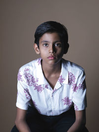 Portrait of young woman standing against gray background
