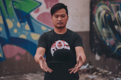 Young man standing against graffiti wall