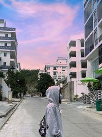 Rear view of woman on street against buildings in city