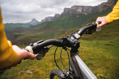 Close-up of a young woman cyclist holding the handlebars of her mountain bike against the backdrop 