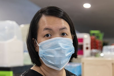 Portrait of woman wearing mask standing indoors