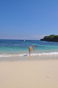 Man backflipping on beach against clear sky